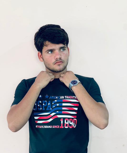 Man wearing a black US Polo Assn graphic t-shirt with American flag design and text 1890