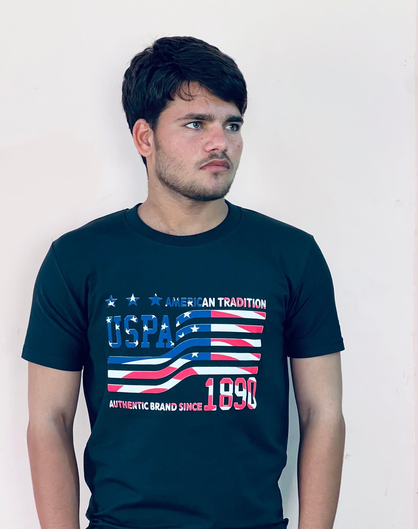 Man wearing a black US Polo Assn graphic t-shirt with American flag design and text on the front