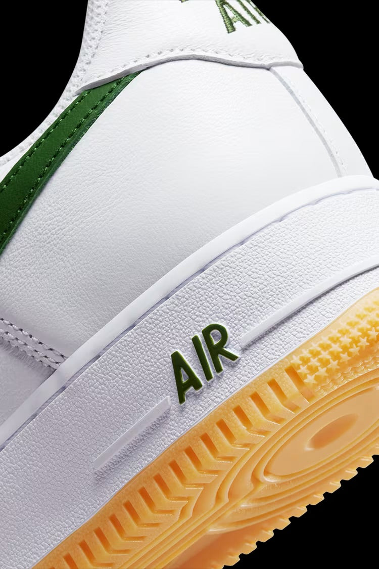 Close-up view of white and green AMBHUS X NIKE AIR FORCE 1 LOW sneaker with textured sole and AIR branding