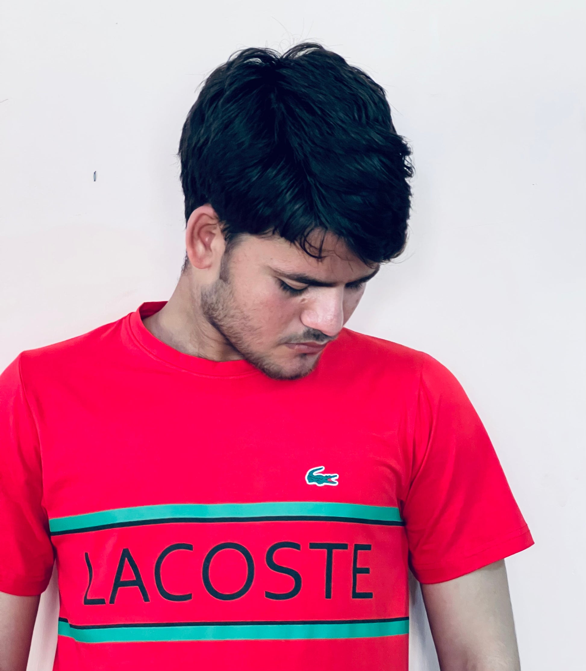 Lacoste red slim fit t-shirt worn by a man looking down with green and black logo print