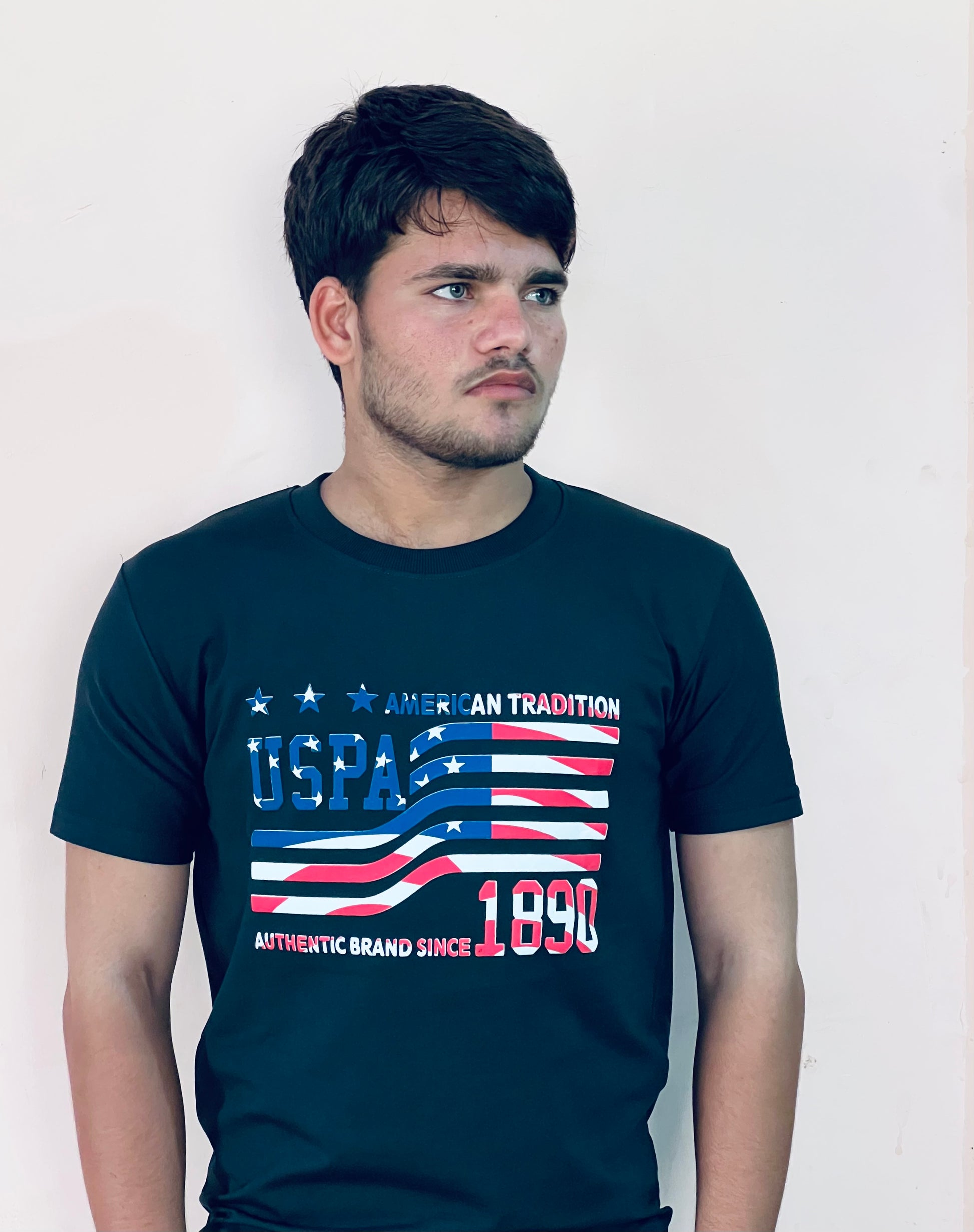Man wearing a black US Polo Assn graphic t-shirt with American flag design and text on the front